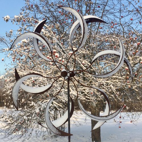 Garden pinwheel with snow and apple tree behind