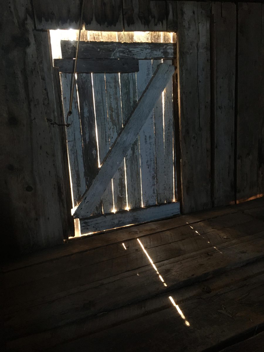 Old barn hayloft door with light shining through.
