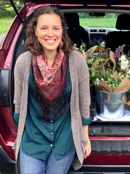 Michelle Darwin leaning against a car with market-ready cut flowers