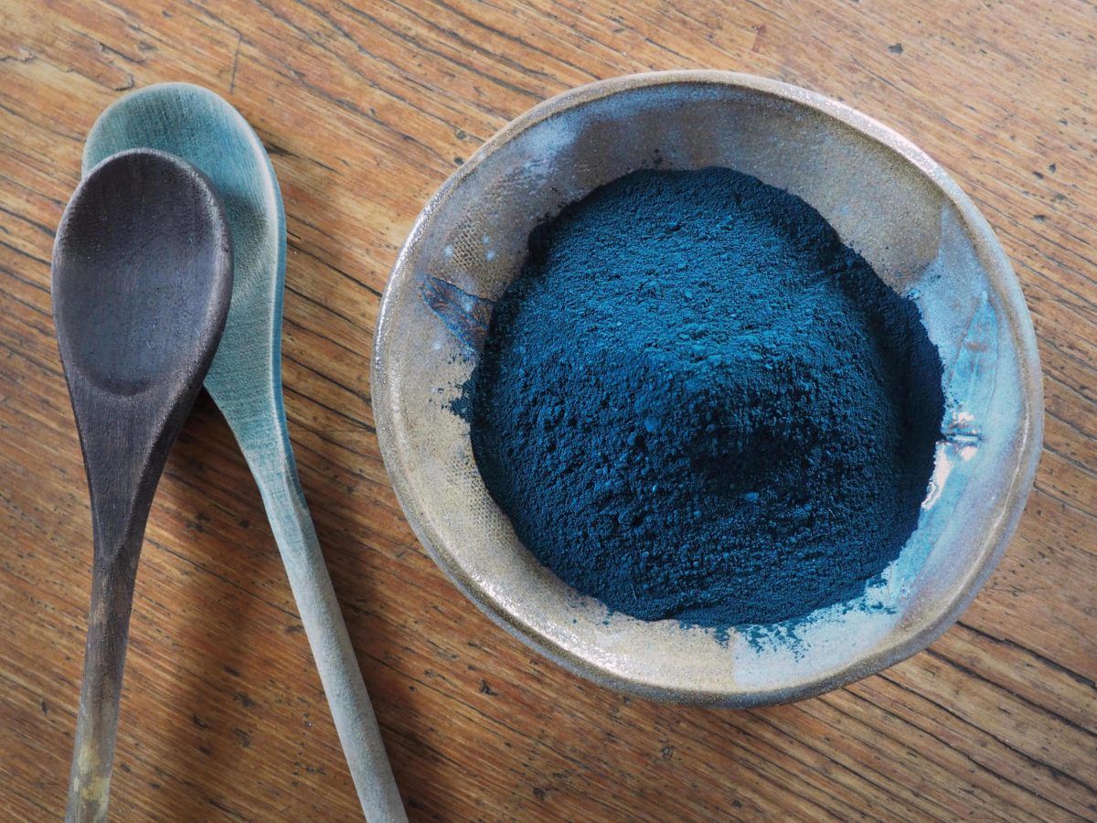 Bowl of indigo powder, wooden dye spoons stained brown and blue